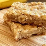 Stack of homemade banana oat bars on wooden board, a healthy and delicious snack.